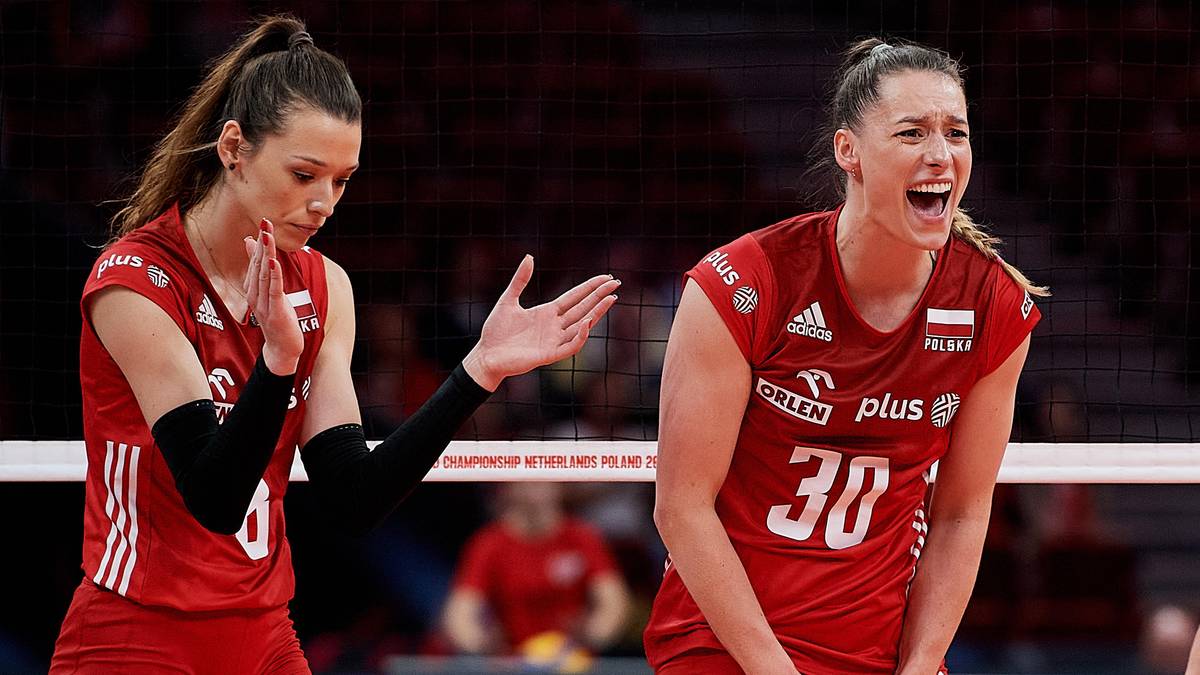 Dwie siatkarki w czerwonych strojach sportowych z numerami na plecach, jedna pokazuje gest dłonią, druga krzyczy z wysiłku.