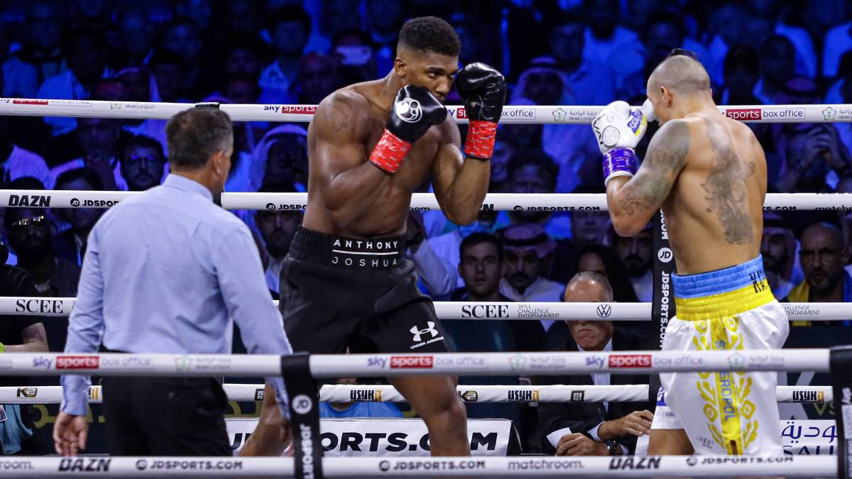 Dwóch bokserów w ringu podczas walki, sędzia obserwuje pojedynek.