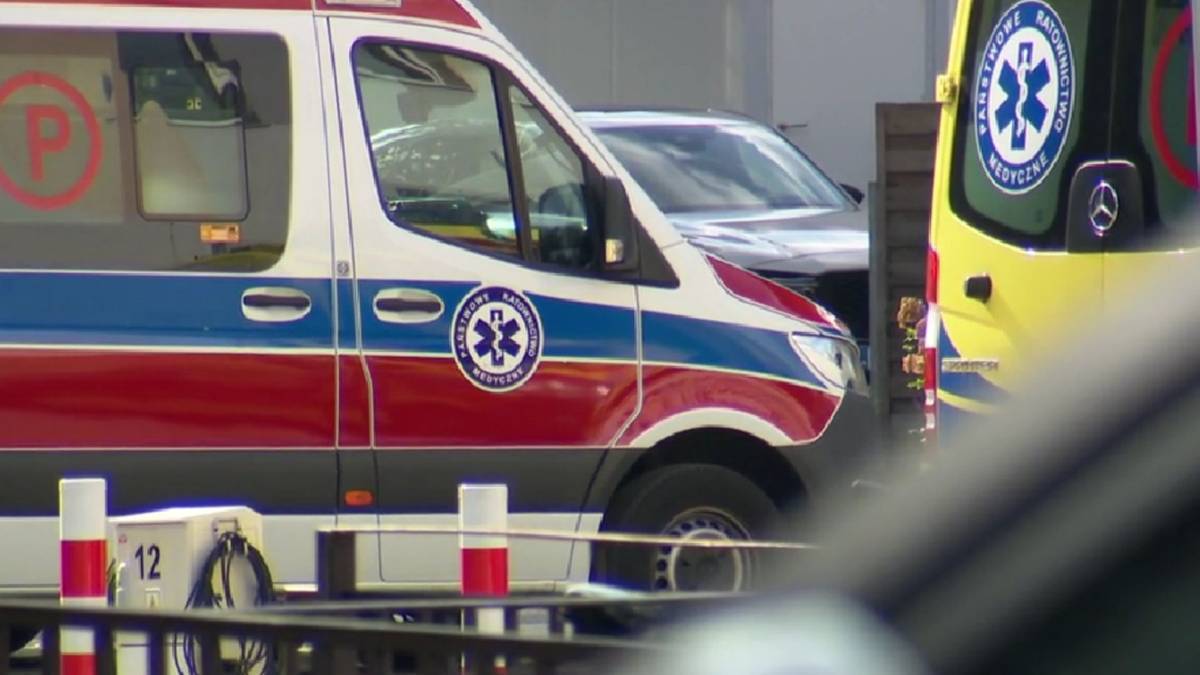 Zbliżenie na bok karetki pogotowia ratunkowego z widocznym czerwono-niebieskim pasem i emblematem ratunkowym.