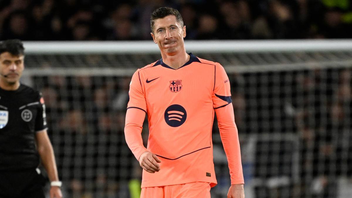 Piłkarz Robert Lewandowski w pomarańczowej koszulce piłkarskiej na boisku.