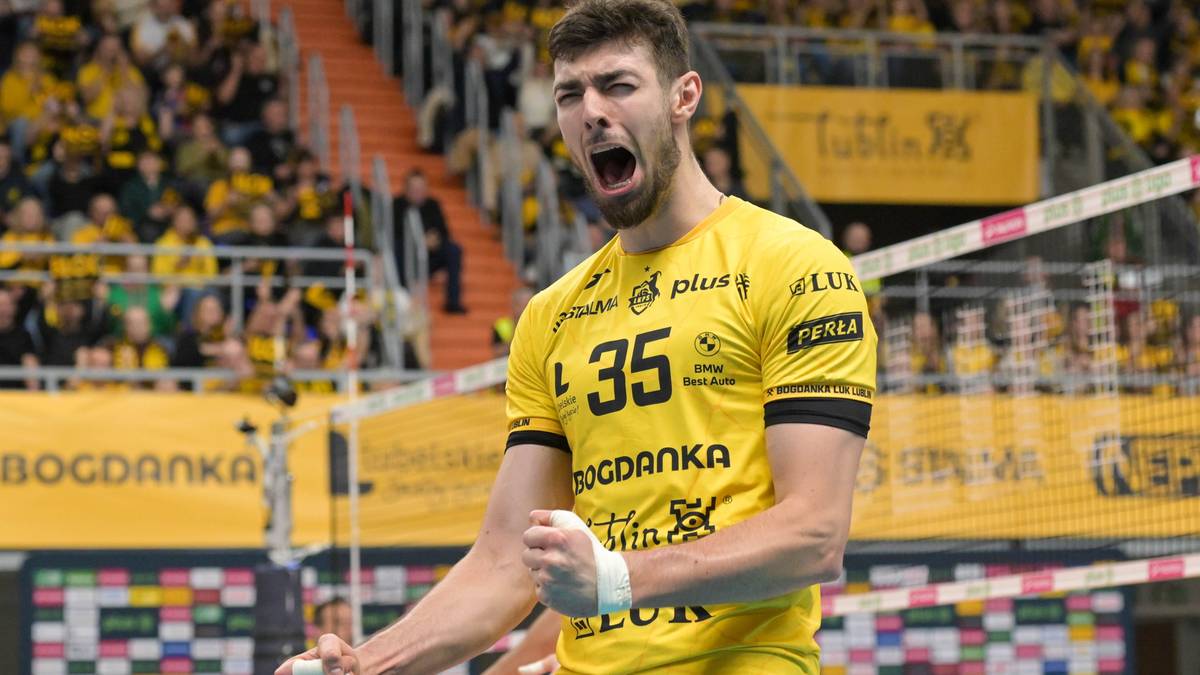 Siatkarz w żółtej koszulce z numerem 35 krzyczy z radości, zaciśnięte pięści.