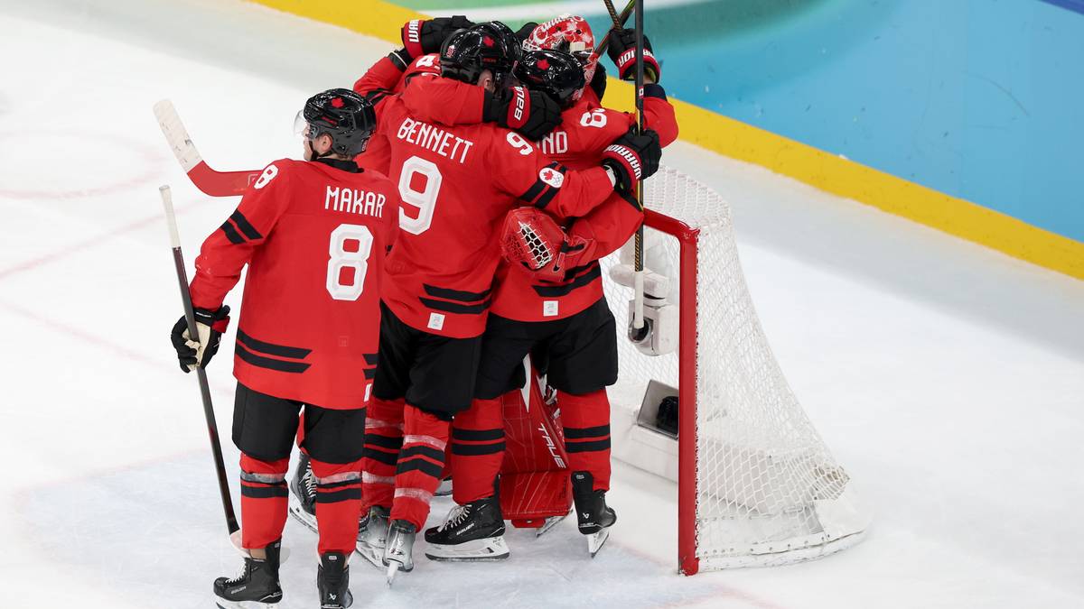 Hokeiści Kanady w czerwonych strojach świętują zwycięstwo, obejmując się przy bramce.