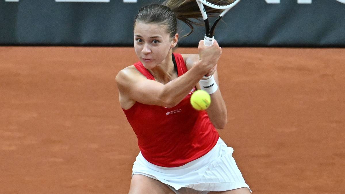 Kobieta grająca w tenisa, odbijająca piłkę rakietą.