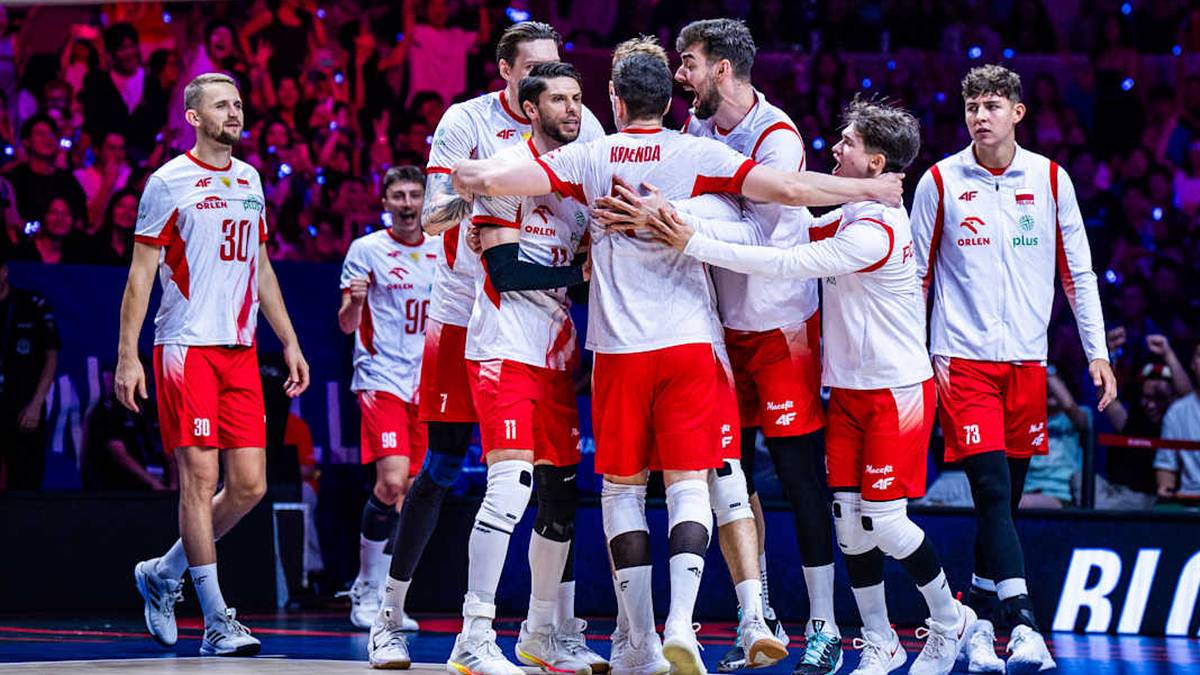 Grupa polskich siatkarzy w biało-czerwonych strojach sportowych obejmuje się na boisku, celebrując zwycięstwo. Na ich twarzach widać radość.