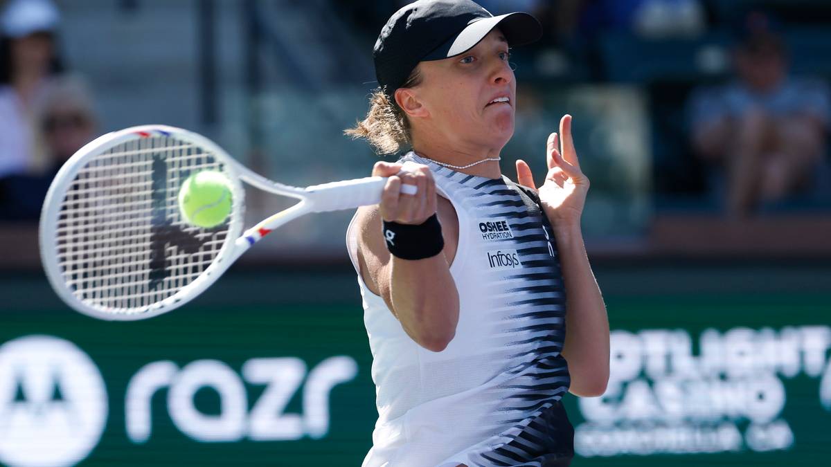 Tenisistka Iga Świątek uderza piłkę rakietą podczas meczu.