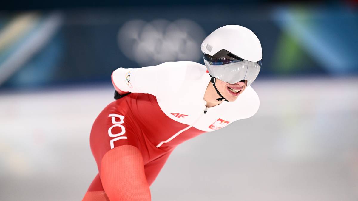 Panczenista w stroju reprezentacji Polski podczas zawod&oacute;w, w kasku i goglach, w ruchu na lodowisku.