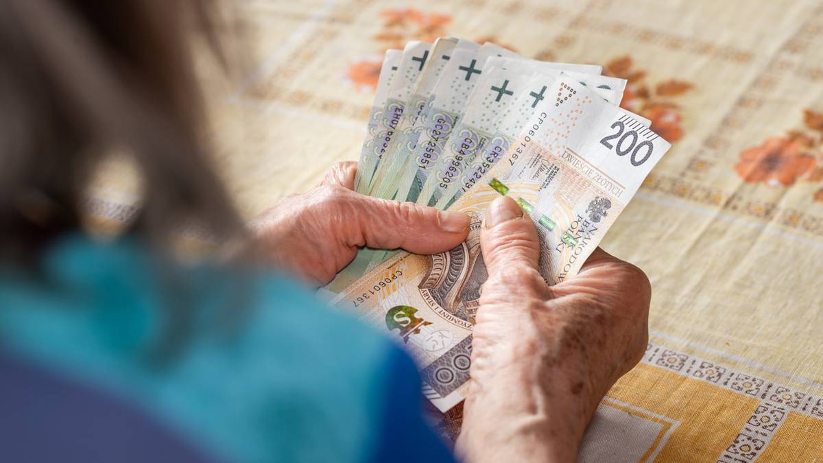 Dłoń starszej osoby licząca banknoty 200 złotych i mniejsze nominały.