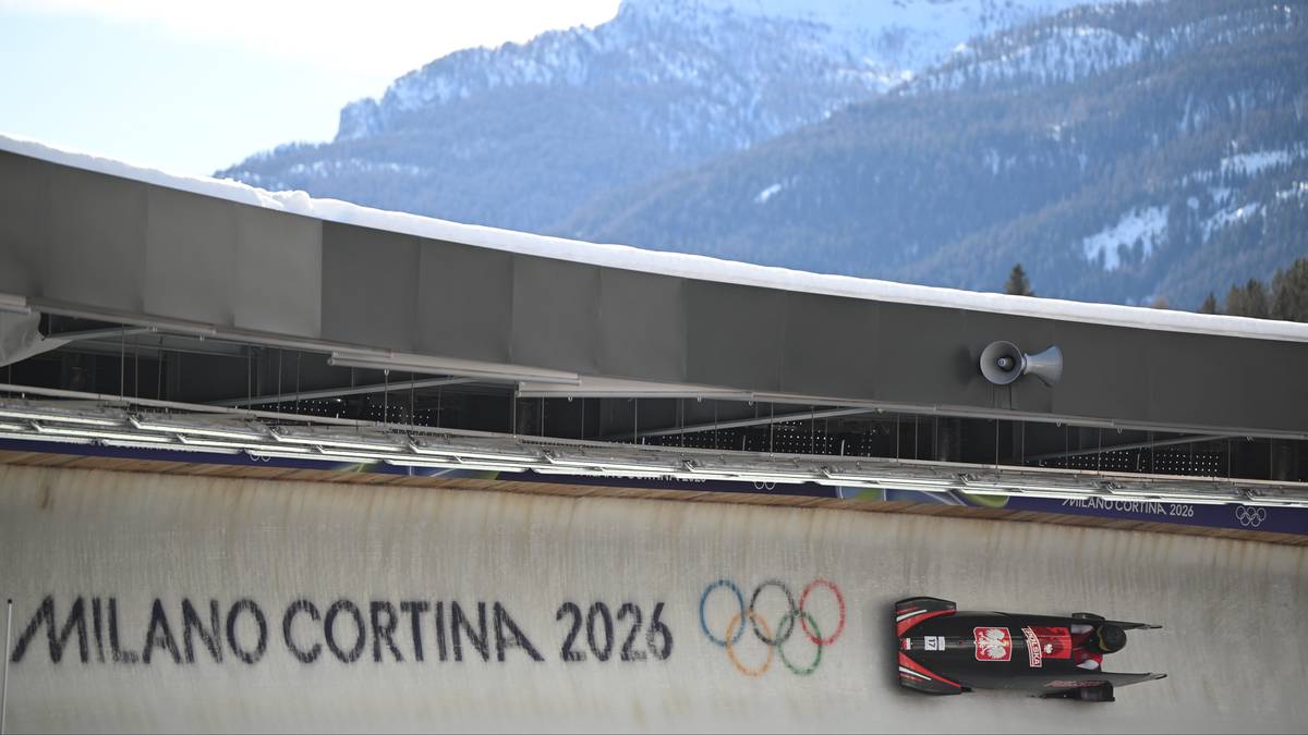 Tor saneczkowy z napisem "MILANO CORTINA 2026" i symbolem igrzysk olimpijskich, obok znajduje się bobslej z polską flagą.