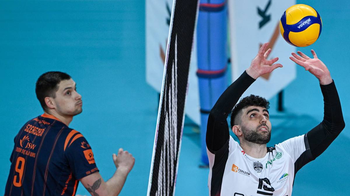 Siatkarz wykonuje zagrywkę, drugi siatkarz w tle