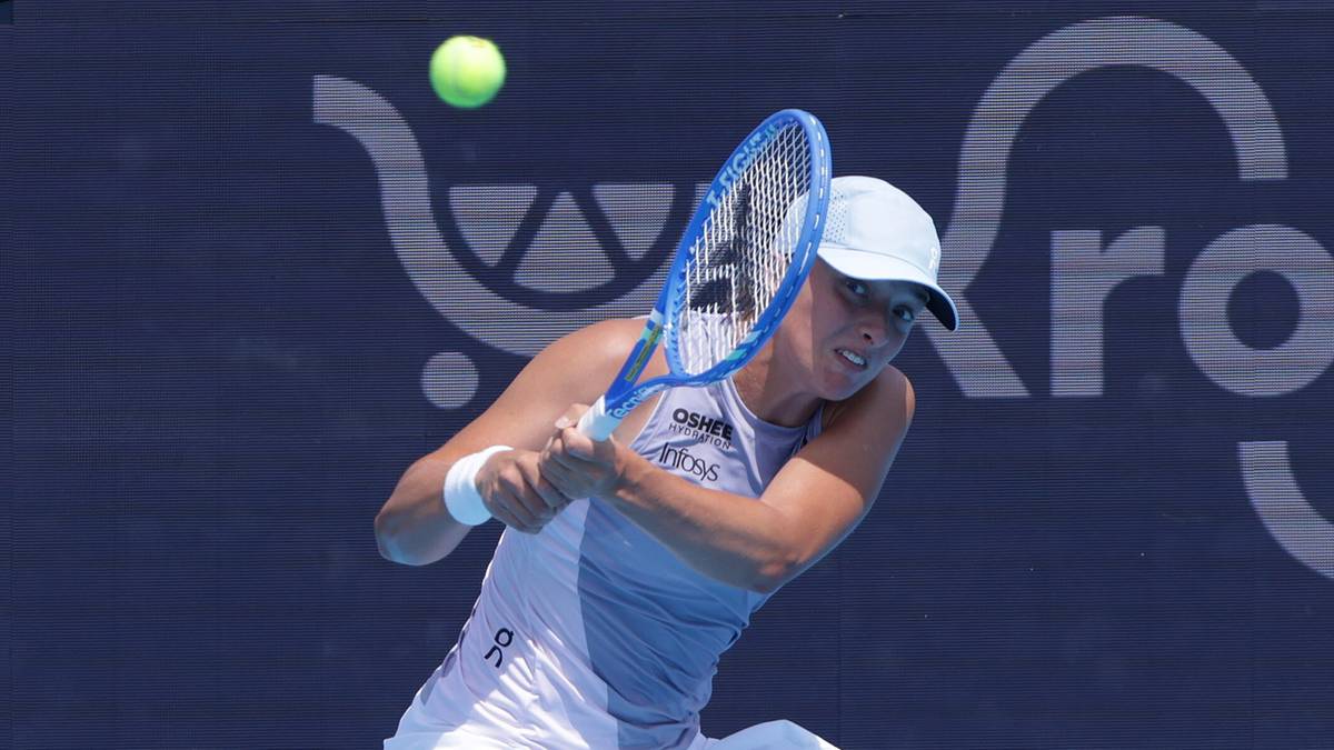 Iga Świątek podczas meczu tenisowego, z rakietą gotową do uderzenia w piłkę.