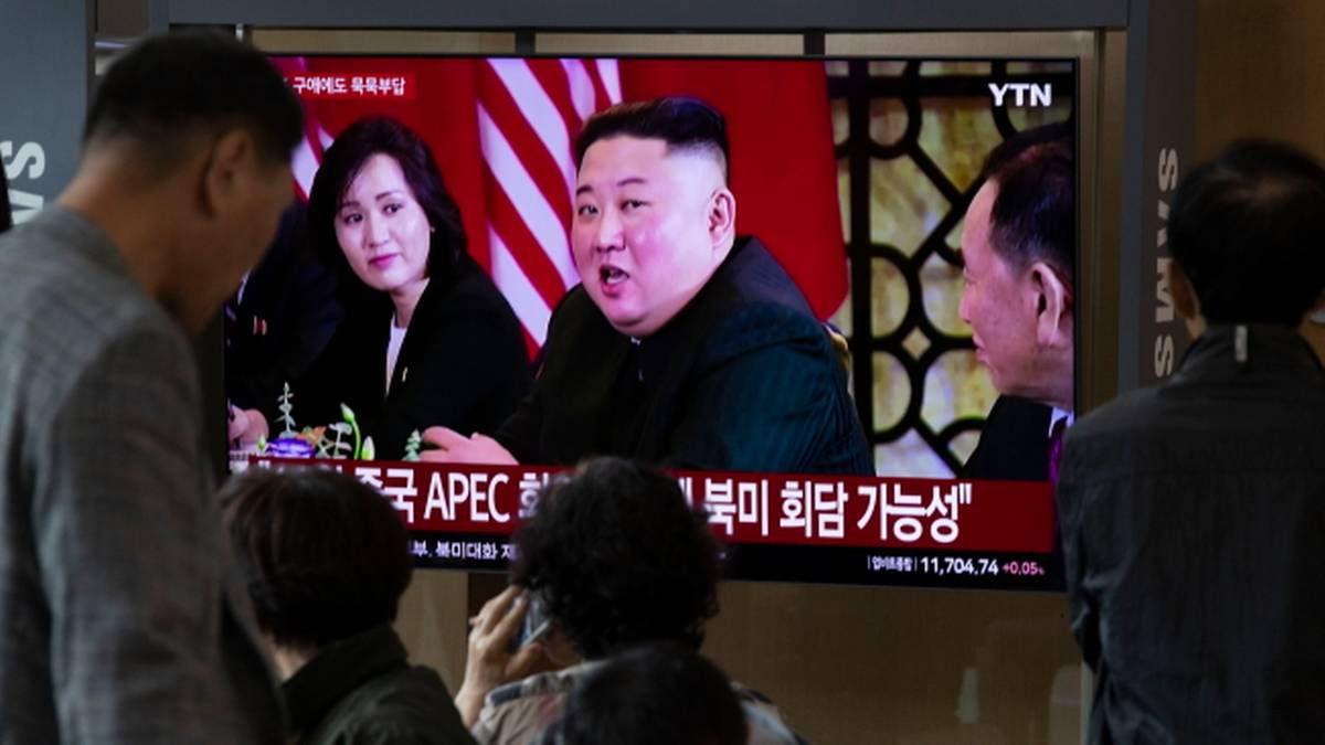 Telewizor pokazujący przywódcę Korei Północnej Kim Dzong Una, obserwowany przez grupę ludzi.