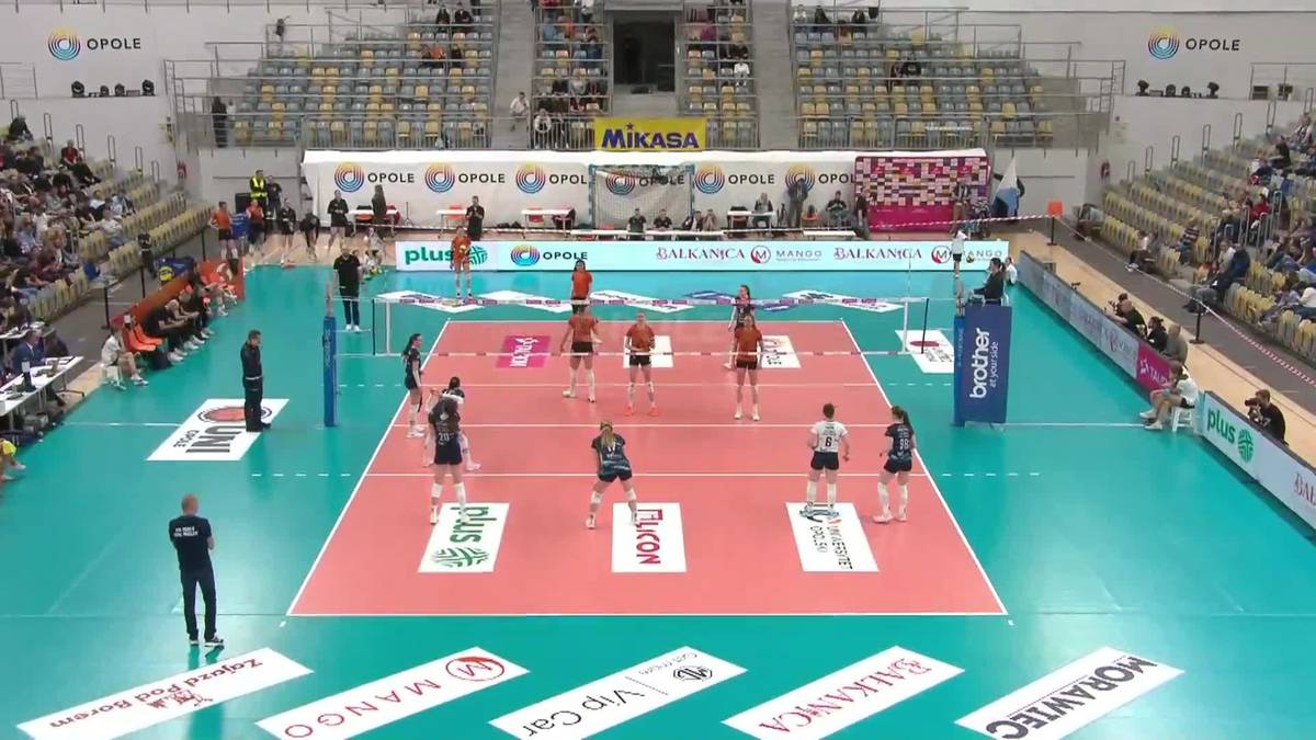 Boisko do siatk&oacute;wki z zawodniczkami i kibicami na trybunach podczas meczu.