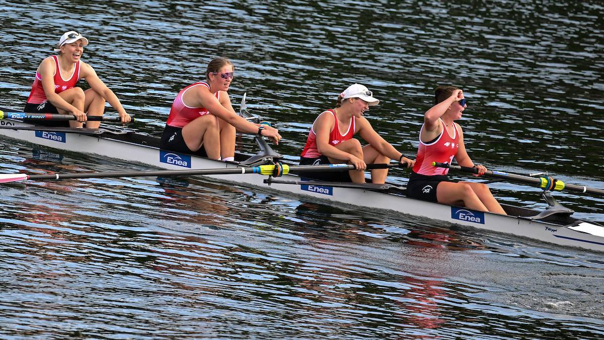 Cztery zawodniczki na łodzi wioślarskiej zmagają się z falą.