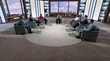 Sześć os&oacute;b siedzi w kręgu w studio telewizyjnym podczas dyskusji politycznej.