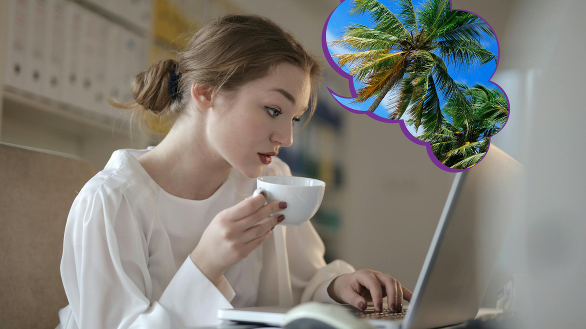 Kobieta siedzi przy biurku, pijąc kawę i myśląc o wakacjach.