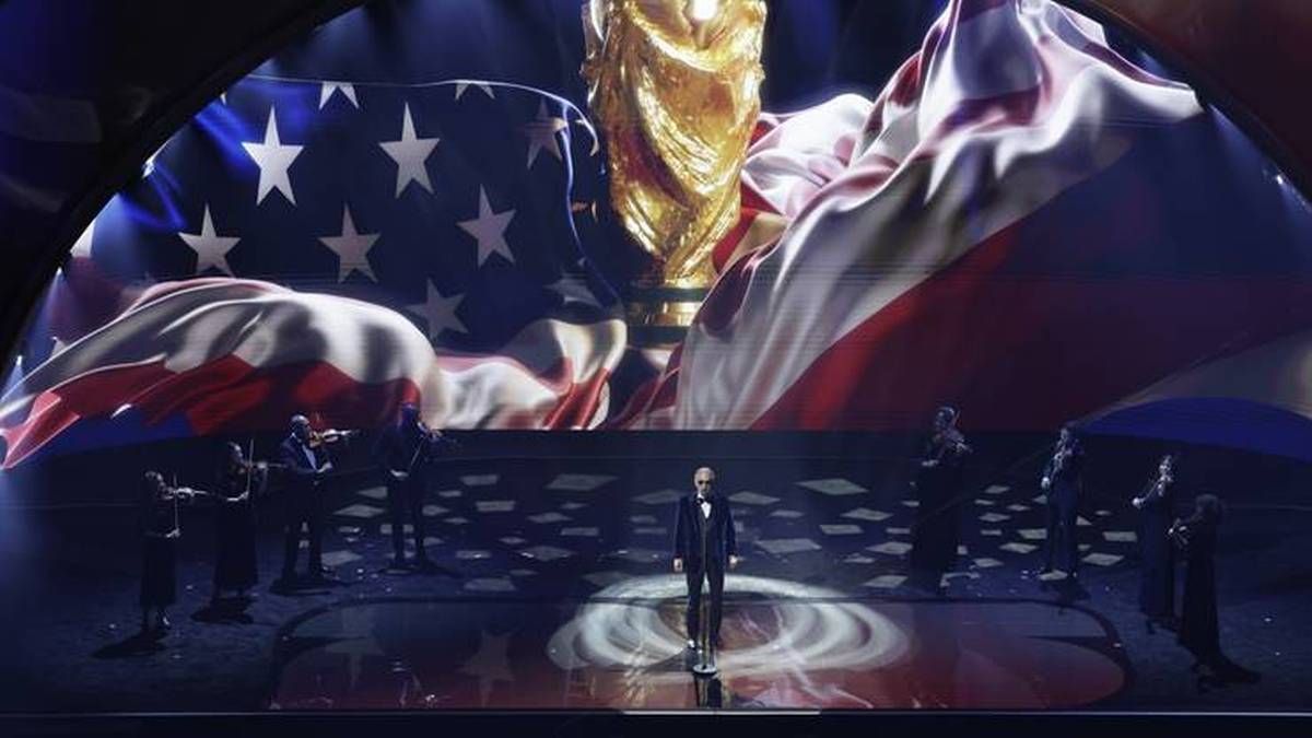 Scena z pucharem świata, flagami USA i Meksyku oraz występującymi na niej osobami.