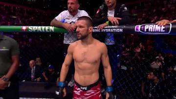 Mateusz Gamrot w stroju sportowym stoi w oktagonie UFC, przygotowany do walki.