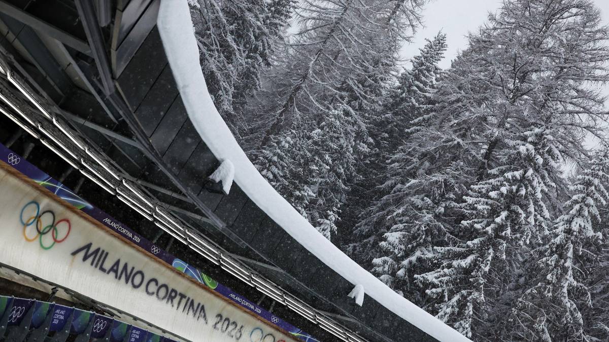 Fragment toru saneczkowego z logotypami Mediolan Cortina 2026 i k&oacute;łkami igrzysk paralimpijskich, na tle ośnieżonych drzew.