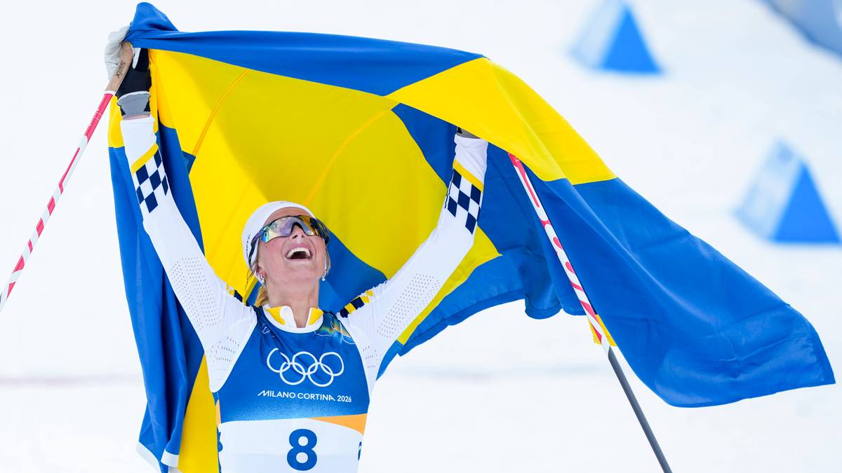 Szwedzka narciarka biegowa Ebba Andersson radośnie unosi flagę Szwecji nad głową, świętując zwycięstwo olimpijskie.