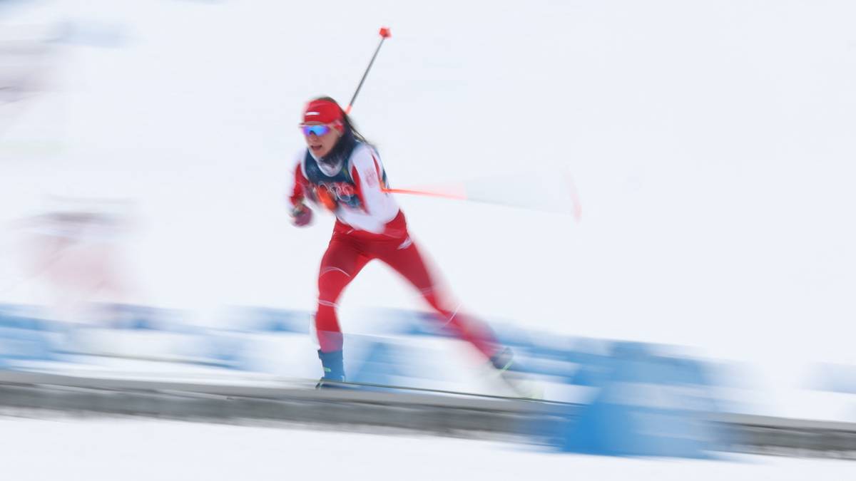 Zawodniczka narciarstwa biegowego w czerwonym stroju jedzie po ośnieżonym stoku.
