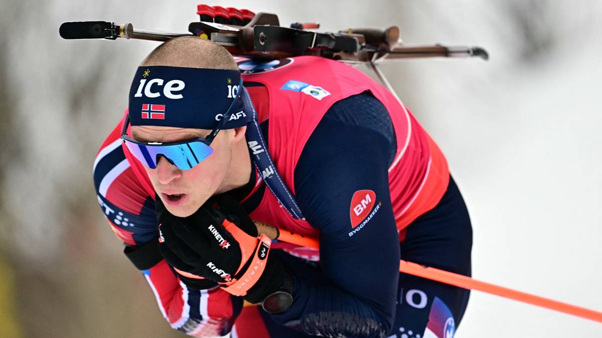 Biathlonista w trakcie zawodów, z karabinem na plecach, pochylony podczas biegu.