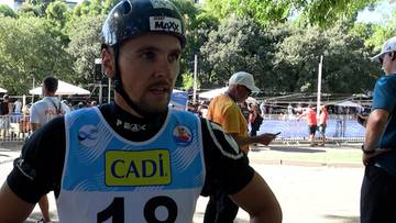 Michał Pasiut w kasku i stroju sportowym z napisem Cadi udziela wywiadu na tle zieleni.