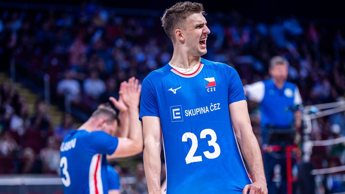 Młody siatkarz w niebieskiej koszulce z numerem 23 krzyczy z radości. W tle widać innych zawodników i publiczność.