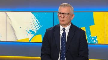 Mężczyzna w garniturze i okularach w studio telewizyjnym