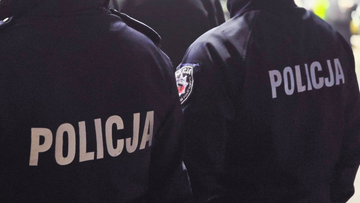 Dw&oacute;ch policjant&oacute;w w policyjnych kurtkach z napisem "POLICJA"