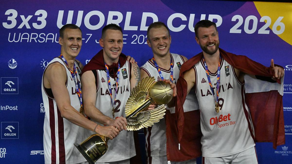 Czterech mężczyzn w strojach koszykarskich trzymających trofeum.