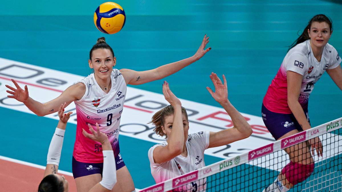 Siatkarki walczą o piłkę przy siatce podczas meczu.