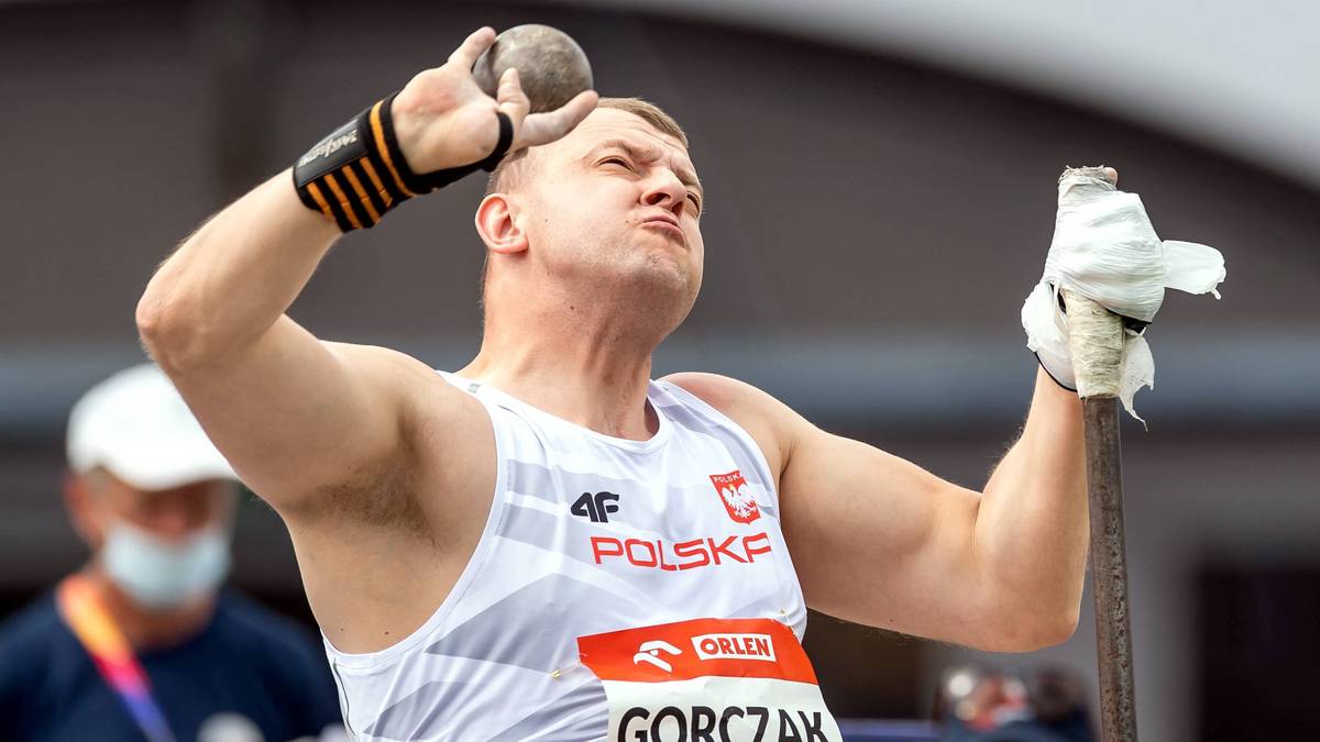 Sportowiec w biało-czerwonej koszulce z napisem "POLSKA" i nazwiskiem "G&Oacute;RCZAK" rzuca kulą.