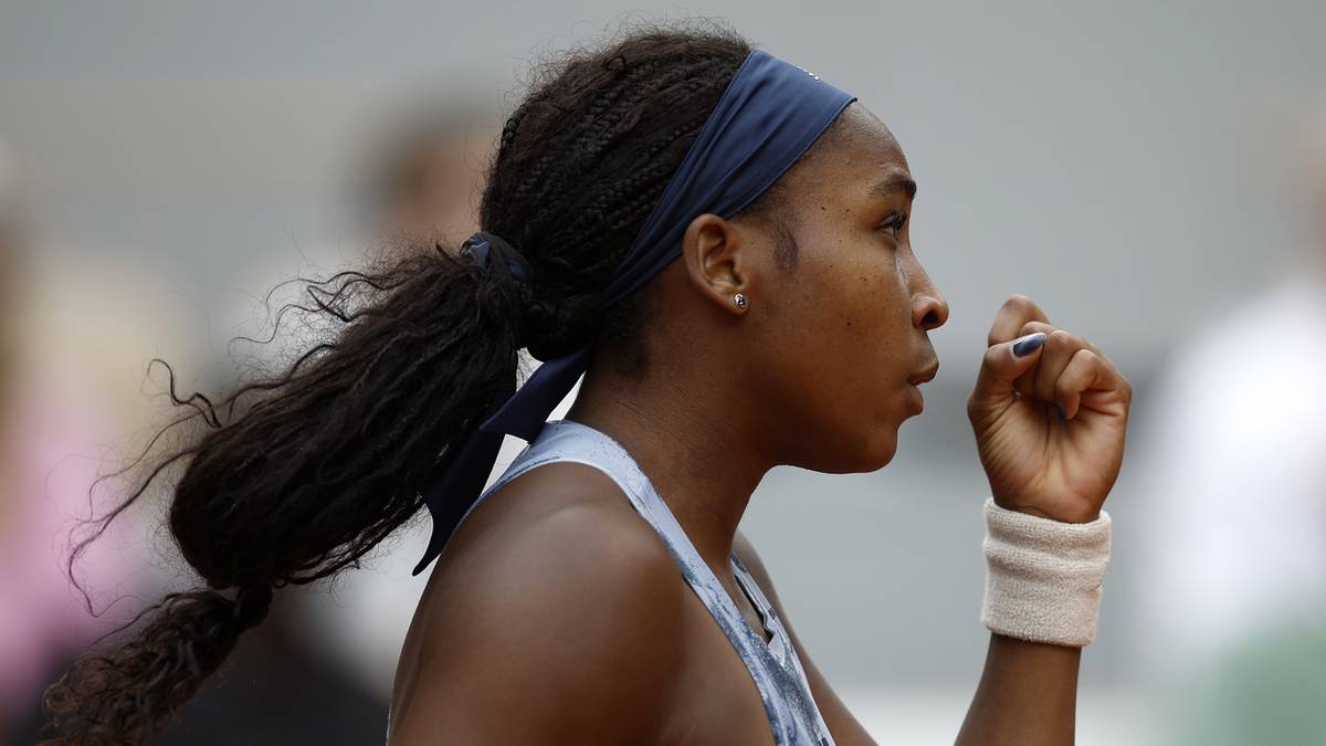 Kobieta tenisistka z opaską na głowie i kucykiem na plecach, w profilu, patrząca przed siebie.