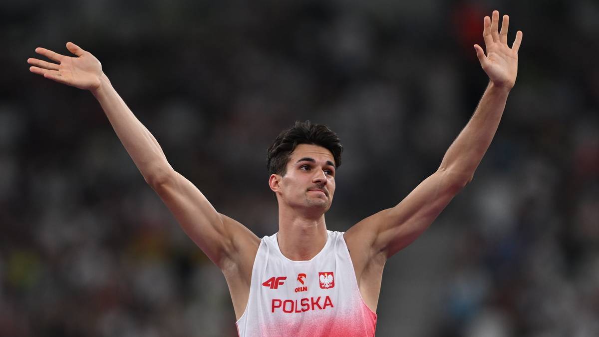 Lekkoatleta w biało-czerwonej koszulce z napisem "Polska" i "Kołodziejski" podnosi ręce w geście radości.