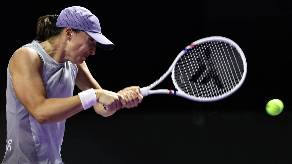 Iga Świątek podczas meczu tenisowego, uderzająca piłkę rakietą.