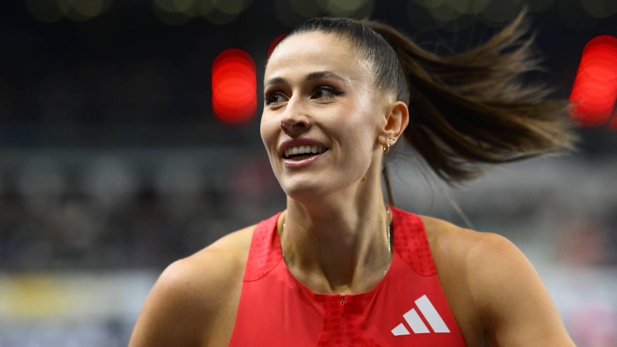 Lekkoatletka w czerwonym stroju sportowym z logo ORLEN, z włosami związanymi w kucyk, uśmiecha się.