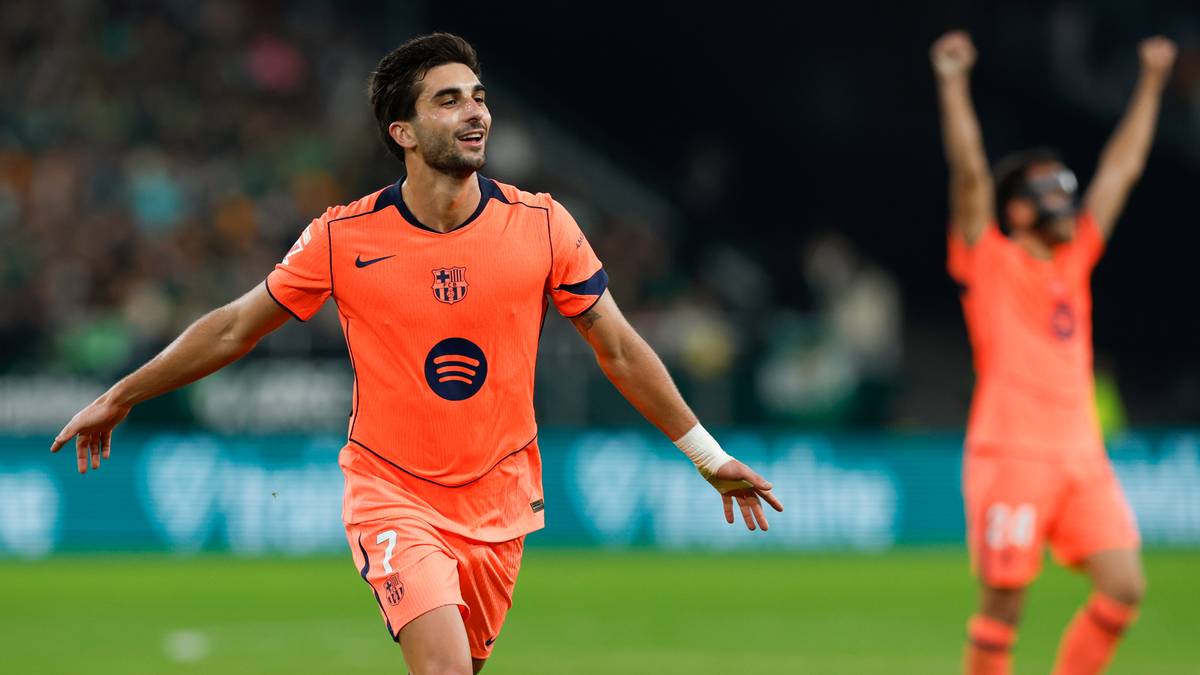 Piłkarz FC Barcelony w pomarańczowej koszulce cieszy się z bramki, w tle inny zawodnik Barcelony z podniesionymi rękami.