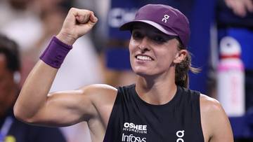 Kobieta w czapce tenisowej i stroju sportowym świętuje z uniesioną pięścią.