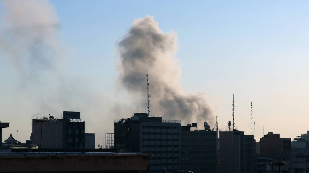 Dym unoszący się nad zabudowaniami miejskimi, widoczny na tle błękitnego nieba.