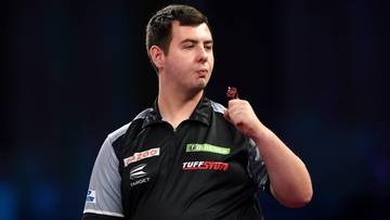 Mężczyzna w koszulce sportowej z logo trzyma rzutkę.