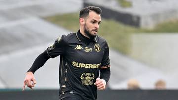 Dwóch piłkarzy na boisku, jeden w czarnej koszulce z numerem 28 na pomarańczowej koszulce.