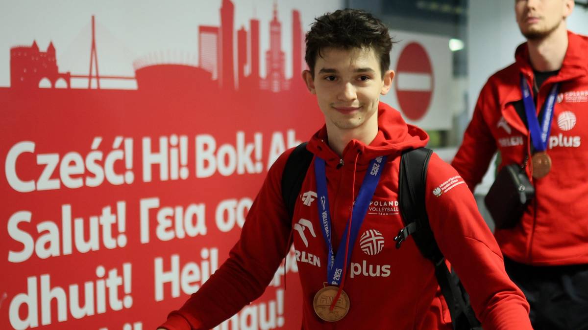 Młody mężczyzna w czerwonej bluzie sportowej z medalem na szyi.