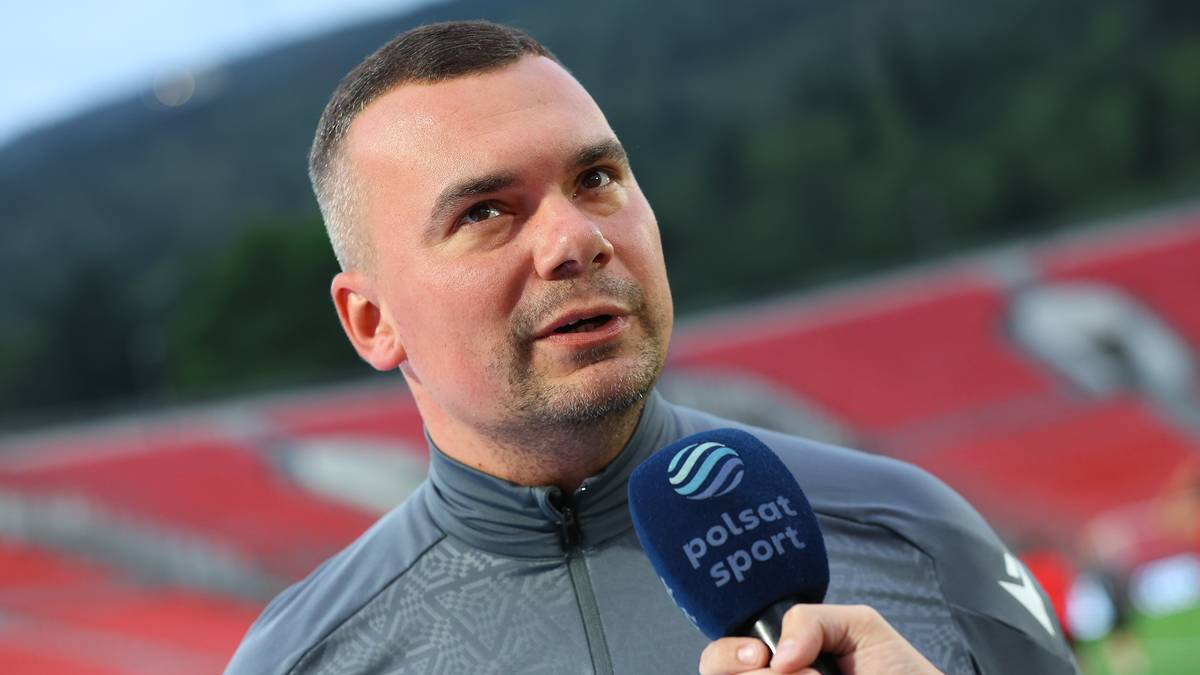 Mężczyzna udziela wywiadu z mikrofonem Polsat Sport na tle stadionu.