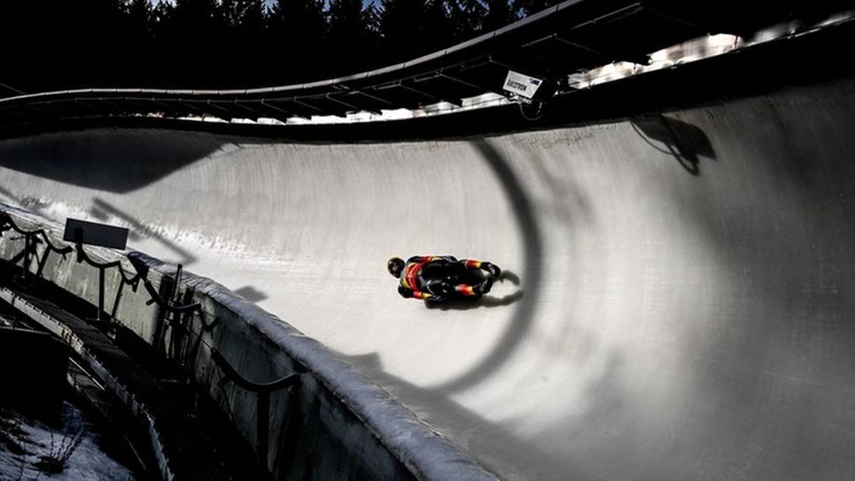 Zawodnik na sankach porusza się po zakręcie wyprofilowanego toru saneczkowego.