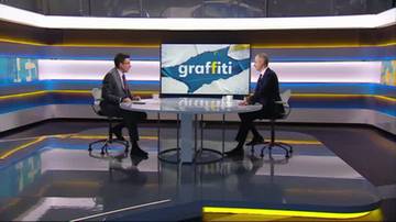 Dwóch mężczyzn siedzi naprzeciwko siebie przy okrągłym stole w studiu telewizyjnym. Na ekranie w tle widnieje napis "graffiti".