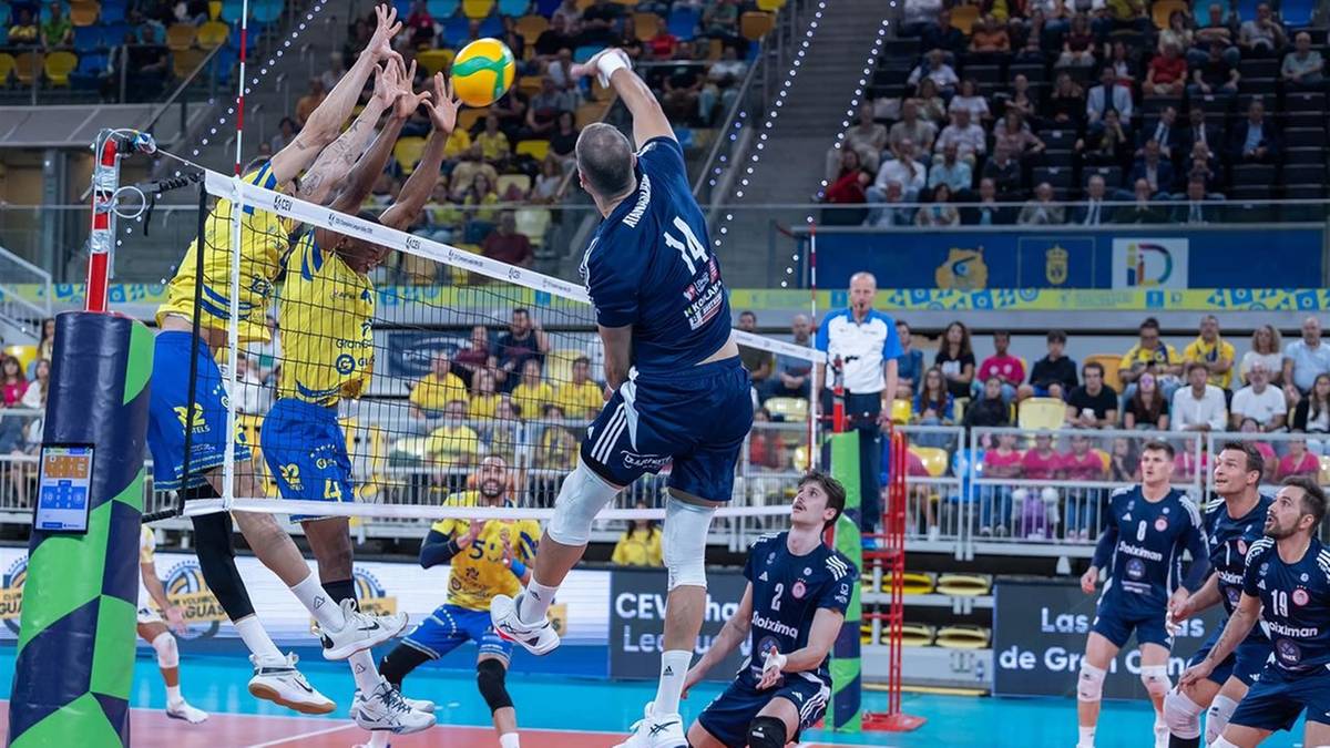 Siatkarze blokują atak przeciwnika nad siatką podczas meczu.