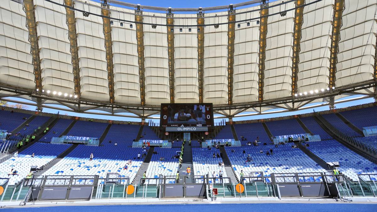 Widok na puste trybuny stadionu piłkarskiego z zadaszeniem i ekranem.