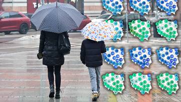 Dwie osoby z parasolami idą chodnikiem.