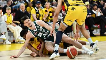 Koszykarze walczący o piłkę na parkiecie podczas meczu.