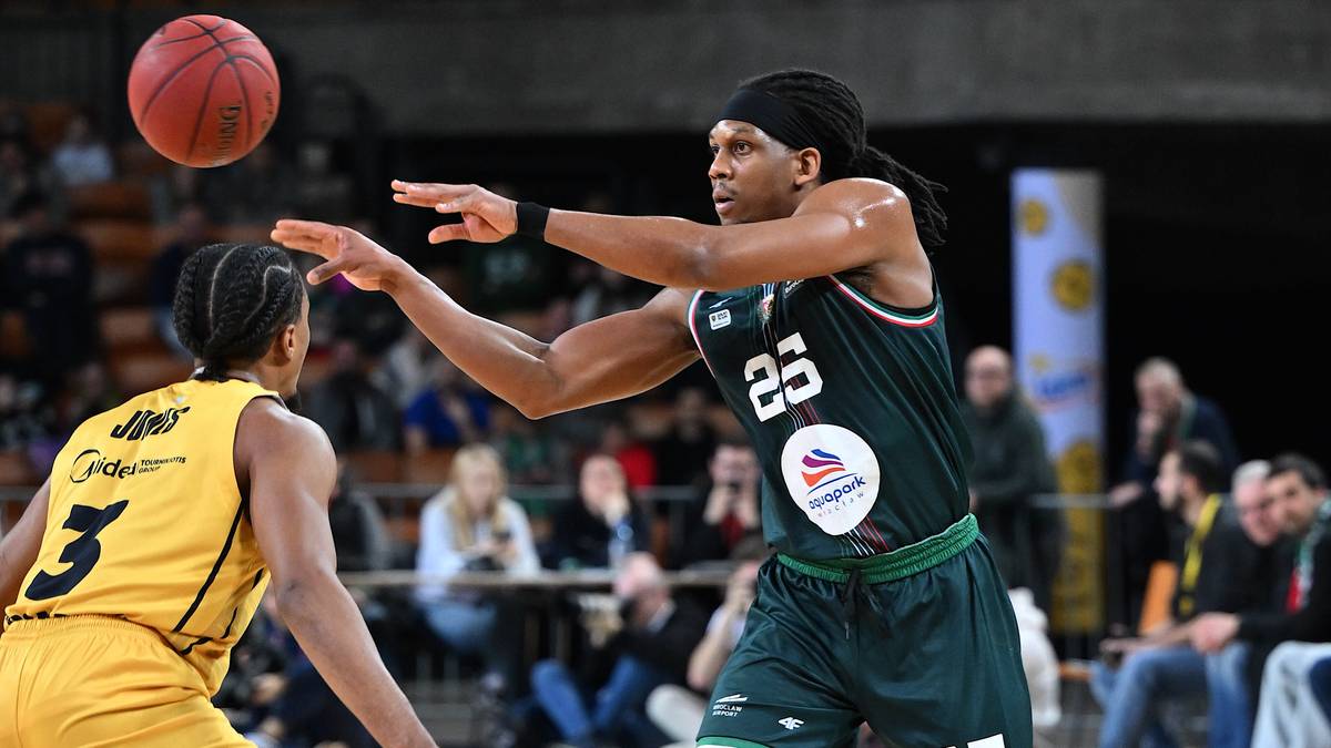 Gracz w zielonym stroju z numerem 25 na plecach rzuca piłkę do kosza, podczas gdy gracz w ż&oacute;łtym stroju z numerem 3 pr&oacute;buje go zablokować.